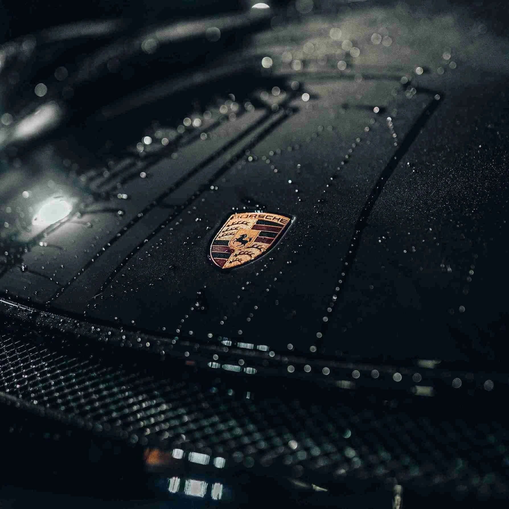 Autolackpflege mit Abperleffekt auf schwarzer Porsche Motorhaube