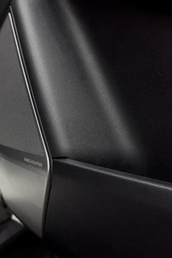 Detailaufnahme des Innenraums eines Fahrzeugs mit glatten Kunststoffoberflächen und hochwertigem Lautsprecher.