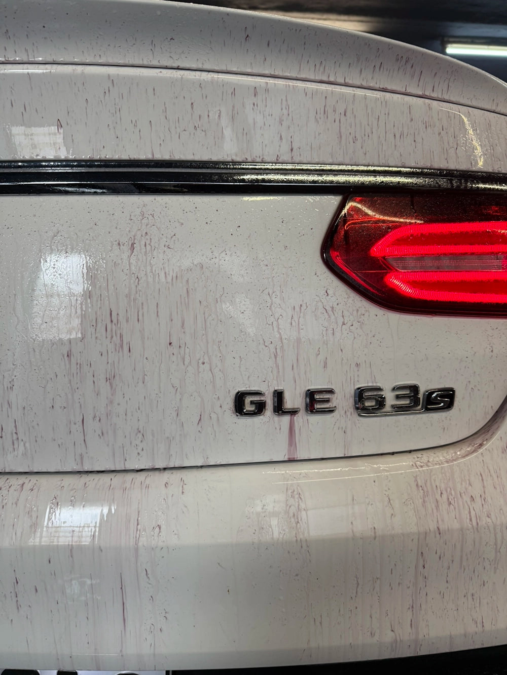 Close-up of a dirty white Mercedes GLE 63s rear, showing rust stains and grime.