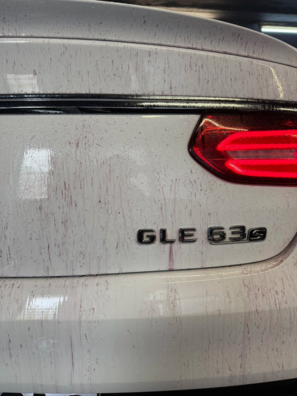 Close-up of a dirty white Mercedes GLE 63s rear, showing rust stains and grime.