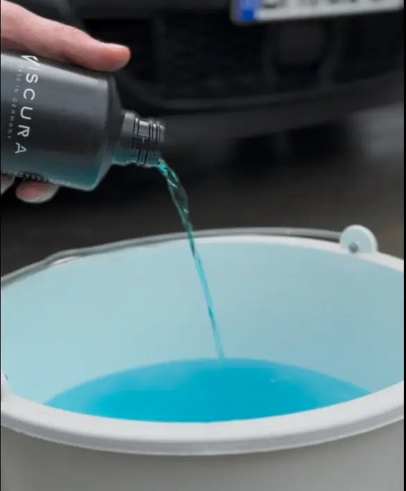 Pouring VISCURA Wax Shampoo into a bucket for optimal car care and maintenance.