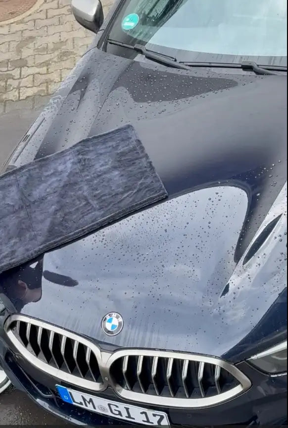 Viscura Trockentuch MAX on a sleek BMW hood, showcasing its water-absorbing capabilities for car drying.