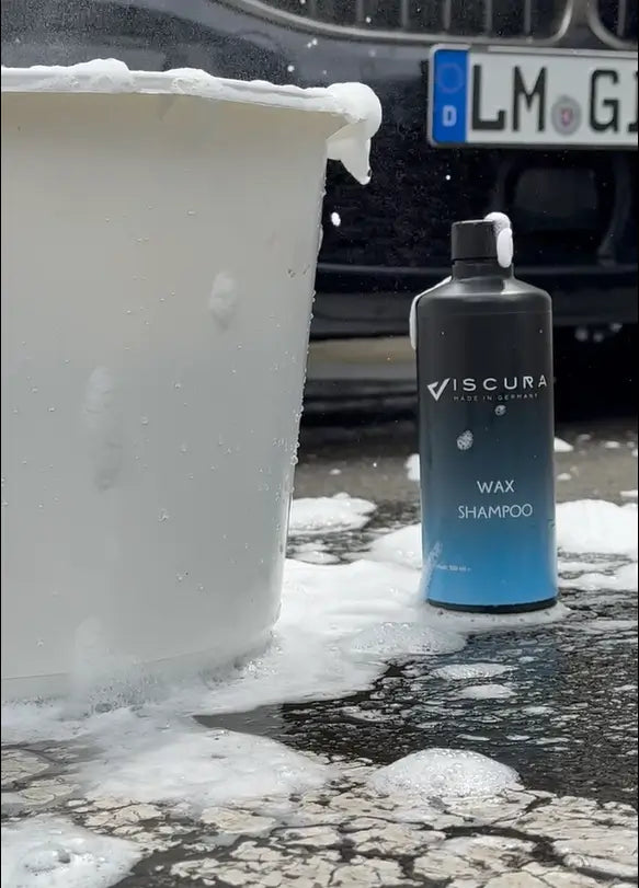 Viscura Wax Shampoo bottle next to a bucket filled with foam, ideal for car cleaning and care.